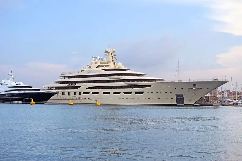 Dilbar under way, seen from astern against a low winter sky, with a second superyacht dwarfed in the foreground.