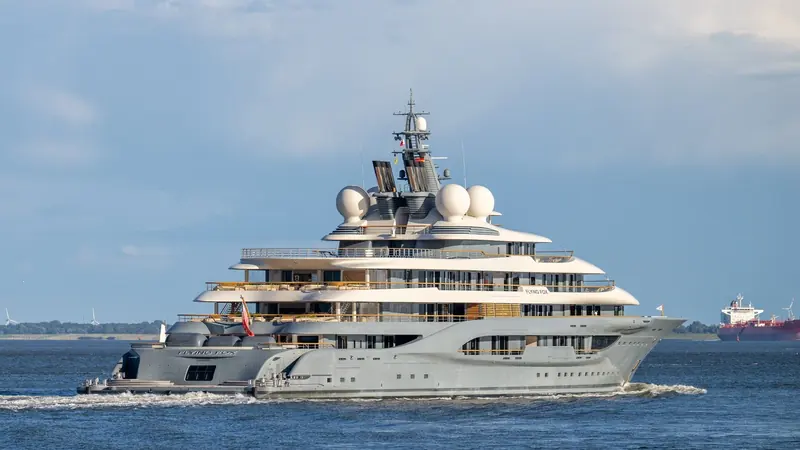 A stern quarter view under way, showing the tender garage doors and the aft beach club deck that opens directly onto the sea.