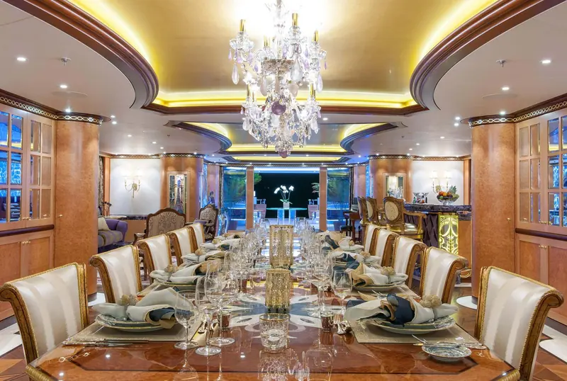 The main-deck dining salon, seated for sixteen under a Schonbek chandelier hung with amethyst and rose quartz crystals, part of Rodriguez Interiors' scheme of roughly 49 marbles and granites and more than 30 woods.