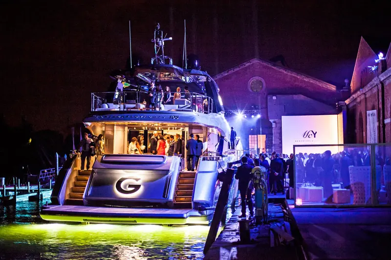 The first MCY 105, named G, is unveiled at a night launch gala inside the Venice Arsenale in July 2015, her transom lit with the owner's chosen name.