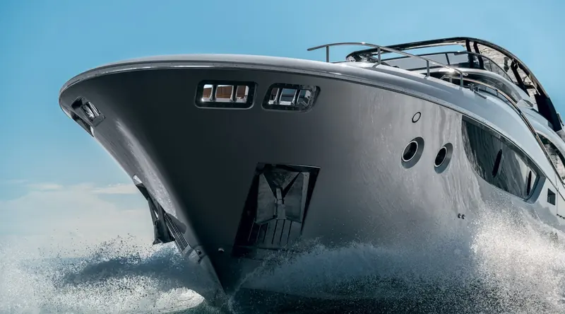Bow-on in a following sea, showing the 16-degree deadrise hull and full-beam forward glazing that light the main-deck owner's suite behind it.