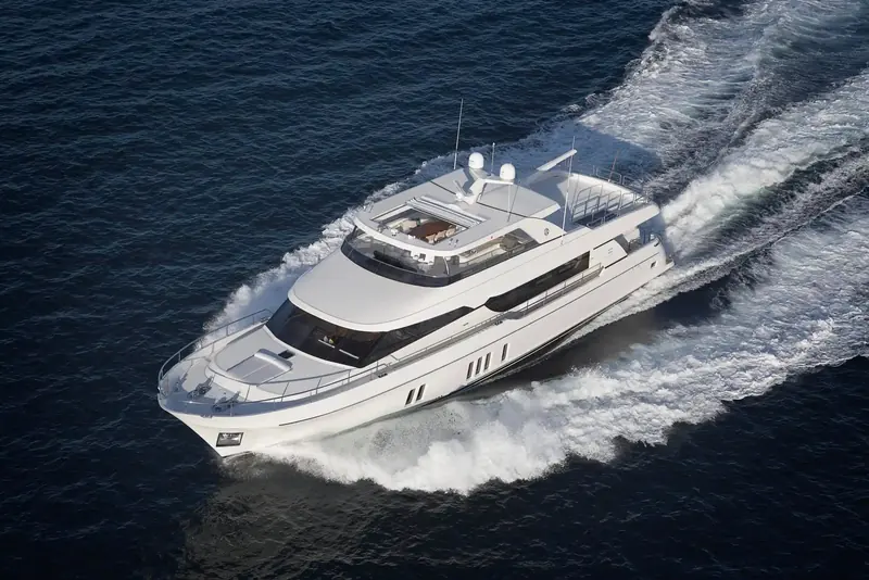 Running shot from above showing the flybridge, hardtop and full length of the 100-foot hull cutting a wake off the coast.