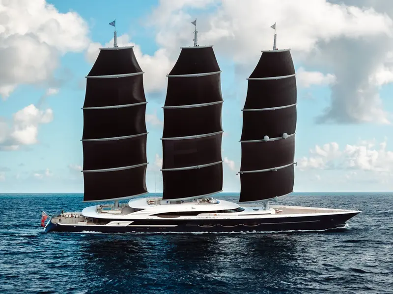 A three-masted Dynarig profile against open sky - the configuration Dykstra Naval Architects engineered so all three masts rotate and trim automatically without deck crew hauling lines.