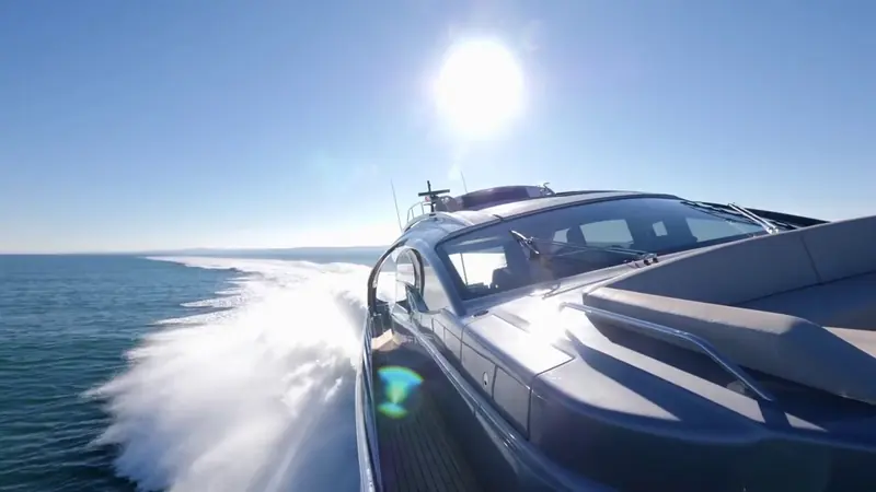 Low-angle running shot into the sun, spray breaking over the bow rail at speed.