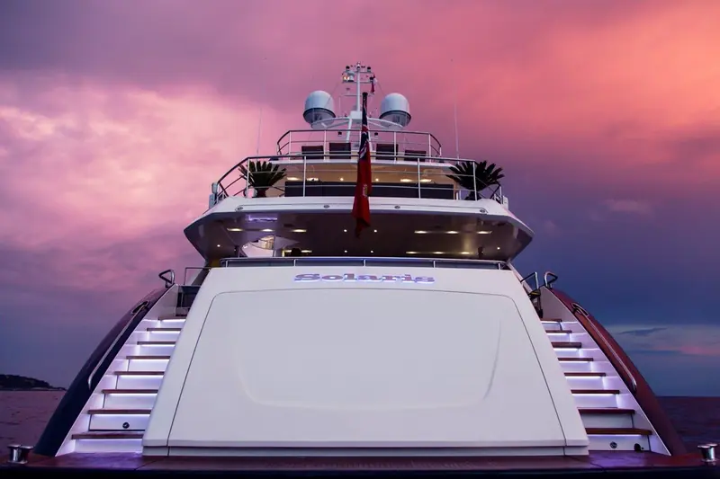 A delivered Princess 40M, named Solaris, moored stern-to at dusk under a storm-lit sky, boarding stairs lit either side of the swim platform.