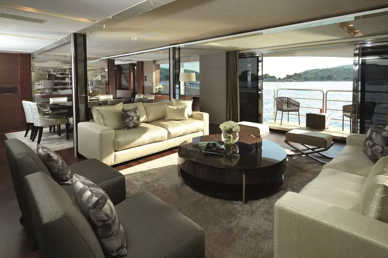 The main-deck saloon of the 40M opens directly onto the aft deck rail through full-height sliding glass, dining table set to port.