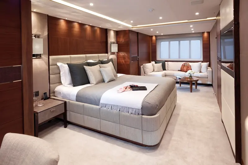 One of the 40M's staterooms, finished in dark wood veneer with a full-beam window seating area beyond the bed.