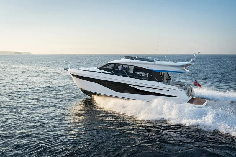 A quieter run at lower speed with the coast behind. This angle gives the clearest read of the lower deck window arrangement and of how much freeboard the F54 carries forward compared with the sportbridge boats in the same size band.