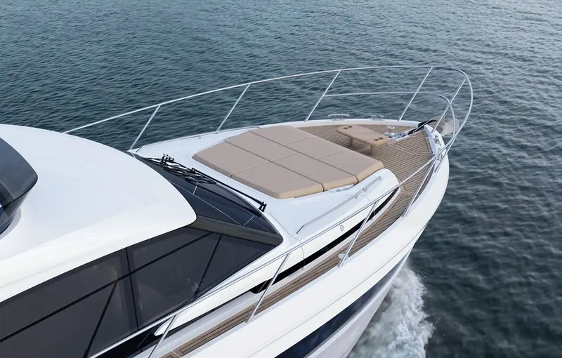 Looking aft along the foredeck sunpad underway, the drop-down windscreen and forward rail giving an idea of how much usable deck the F54 carries ahead of the flybridge superstructure.