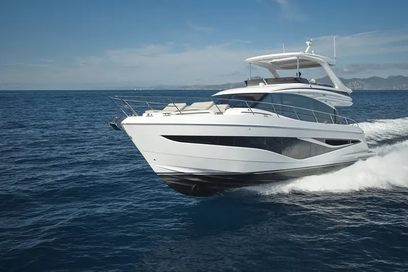 Bow-on running shot showing the F-Class hull's forward flare and the sunpad built into the foredeck, ahead of the raised flybridge helm.