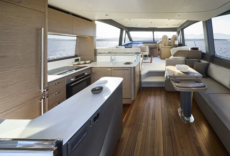 The galley and lower salon in oak, laid out open-plan to the cockpit doors so the boat can be run and entertained from without a crew below.