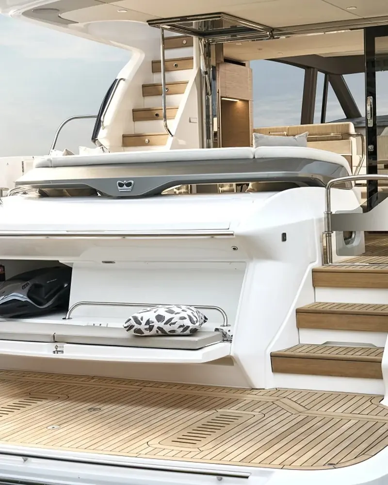 The aft cockpit with its fold-out sunpad and folding table, steps leading up to the flybridge visible at the top of frame.