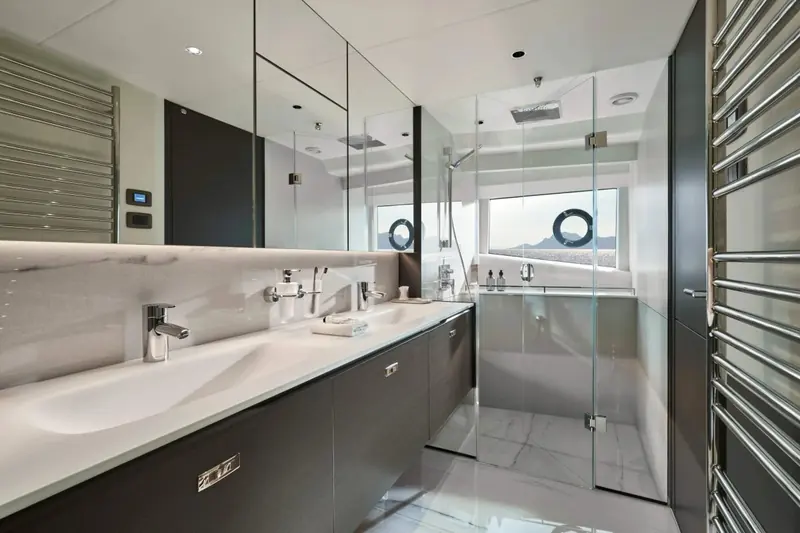 An ensuite bathroom in dark wood and stone, one of five staterooms the Y95 carries in standard layout.