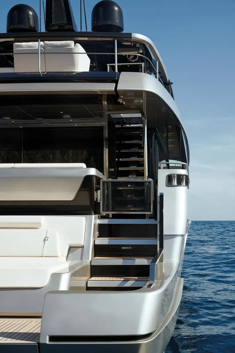 A starboard stairway drops from the flybridge past the boarding gate straight to the swim platform, cutting out an internal deck-to-deck walk.