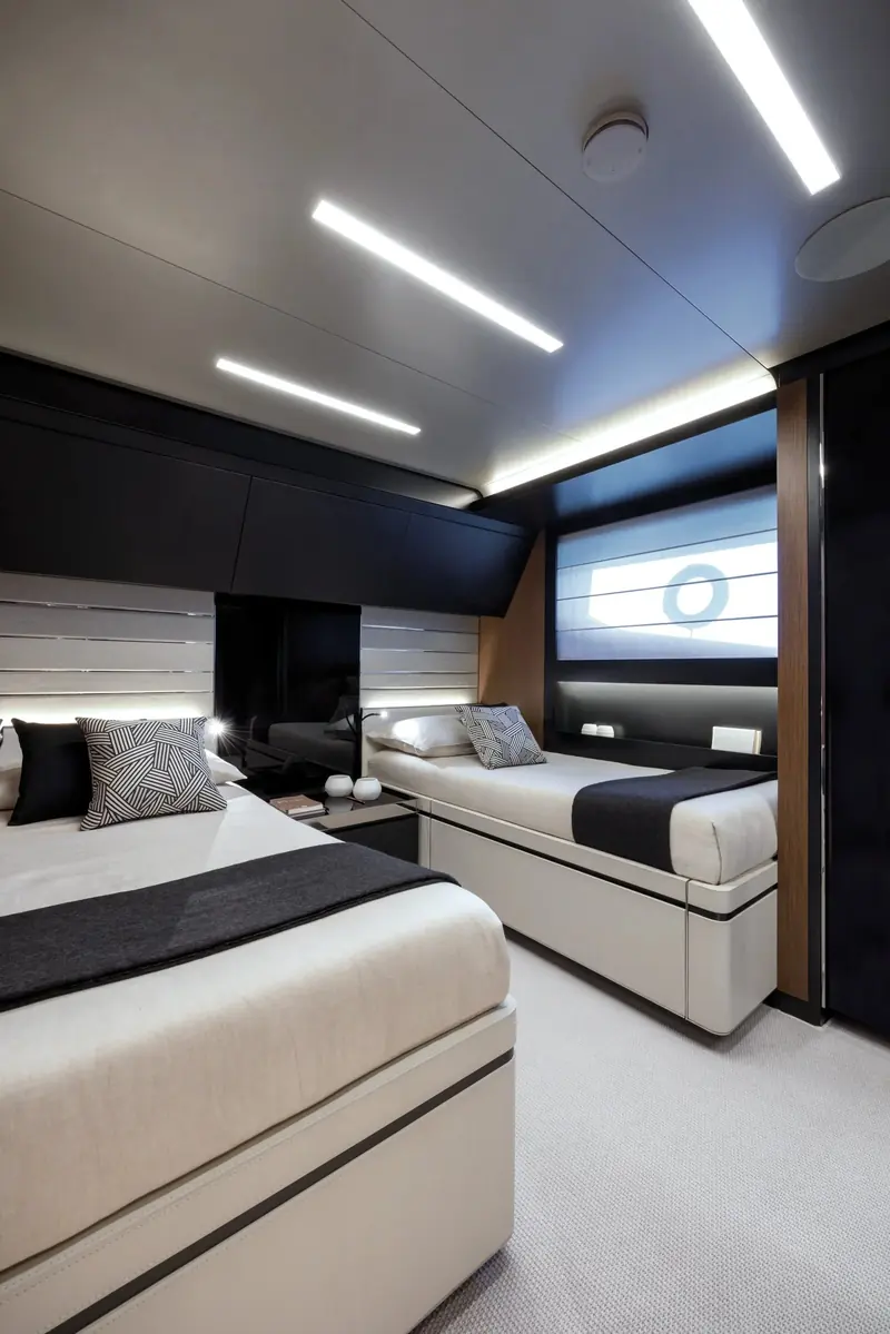 One of the lower-deck twin cabins converts to a double, finished in the same dark oak and leather headboard panelling as the guest suites forward.
