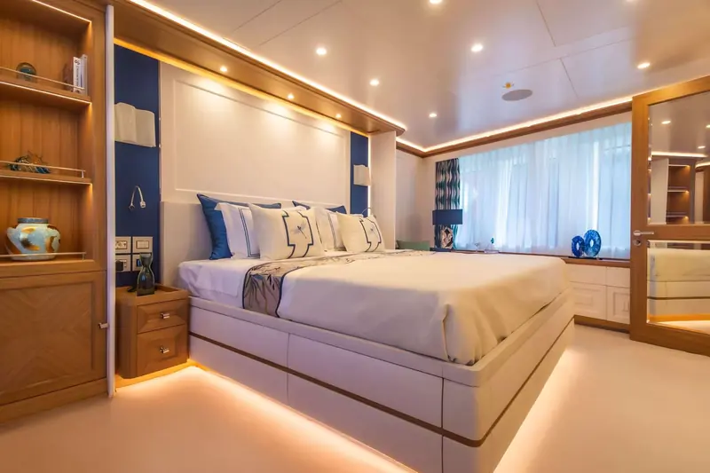 The owner's cabin aboard Seven Seas, with a full-beam window bank and built-in joinery in a warm wood finish