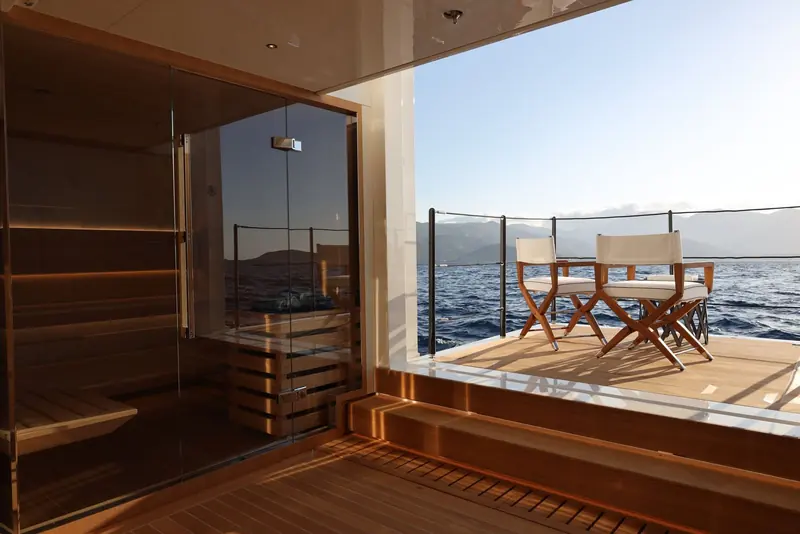 A deck sauna opens directly onto an aft cockpit with director's chairs, an unusual pairing of a dry sauna with open-air deck space rather than tucking it below.