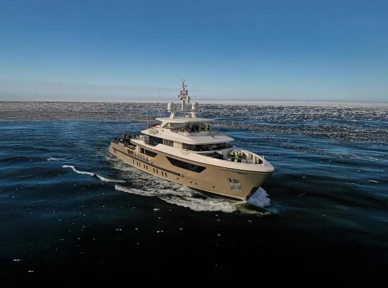 A 500EXP underway through brash ice with crew on the flybridge, the kind of high-latitude cruising Sanlorenzo built the explorer range's ice-class steel hull and helicopter deck to handle.