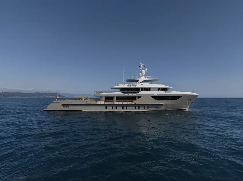 The 500EXP's profile at anchor off the Mediterranean coast: a workboat-style raked bow and low freeboard aft over a steel-and-aluminium hull built to ABS class for ocean passages, not day cruising.