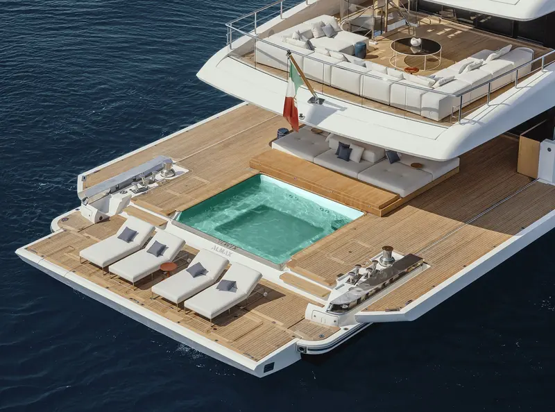 The aft deck at anchor, with a sunken jacuzzi, sun loungers and lounge seating under a hardtop.