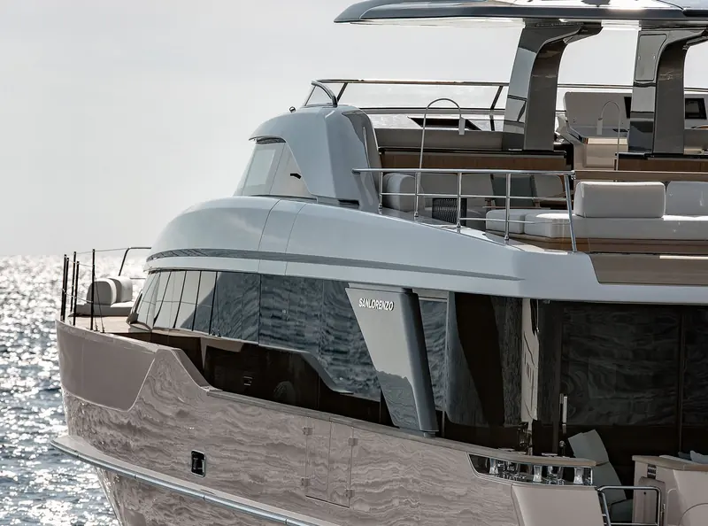 A close view of the aft superstructure and flybridge stairs, mirror-polished hull plating catching the light.