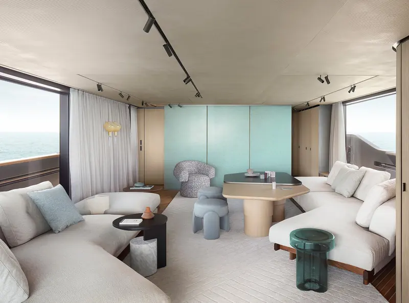 A saloon corner with a curved sofa in pale blue and grey, full-height glazing to one side.