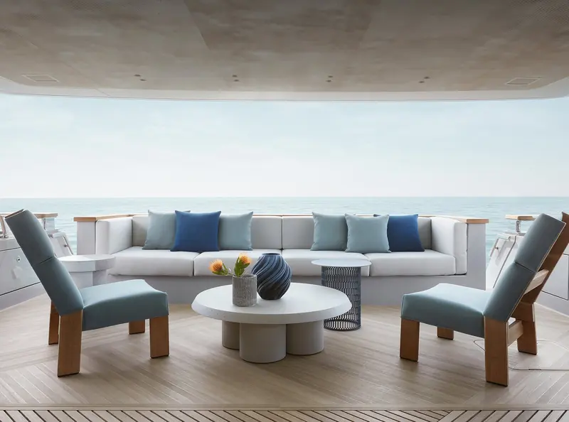 The aft-deck lounge, a full-width sofa facing timber and stone side tables.