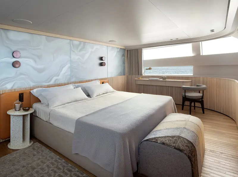 A cabin's headboard wall is backlit onyx-effect glass rather than upholstery, with the reading lights built into the panel itself.