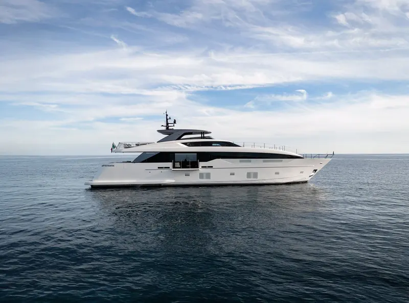 The SL110A underway against a bright sky, sundeck hardtop and open flybridge visible.