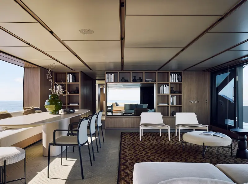 The galley and dining area, joinery in dark wood with a built-in bookcase facing the sea.