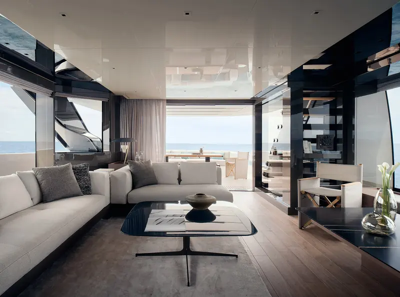 The main-deck saloon opening onto the side deck, a curved sofa and glass coffee table.