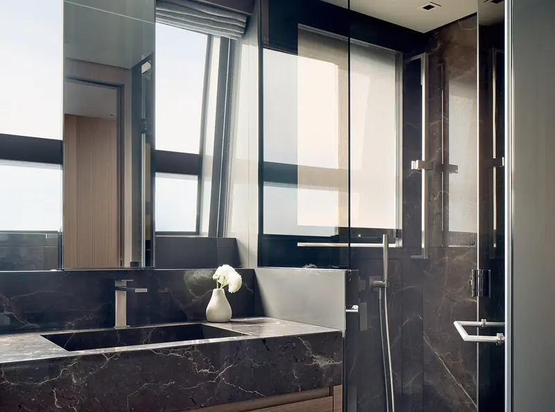 An ensuite bathroom finished in dark marble with a full-height window beside the shower.