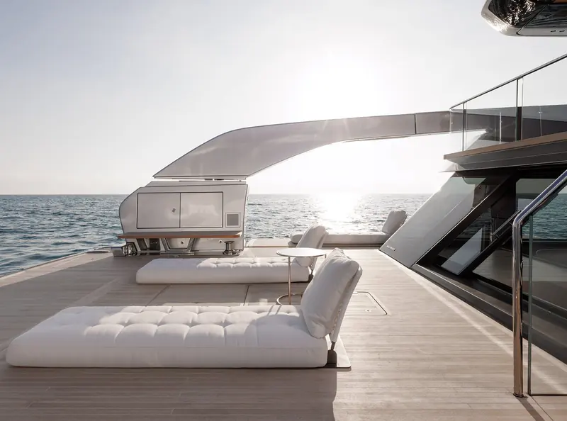 A side deck lounge area at the transition to the flybridge stair, teak decking underfoot.