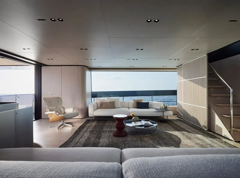 The main-deck saloon, a long sectional sofa facing full-height windows onto the sea.