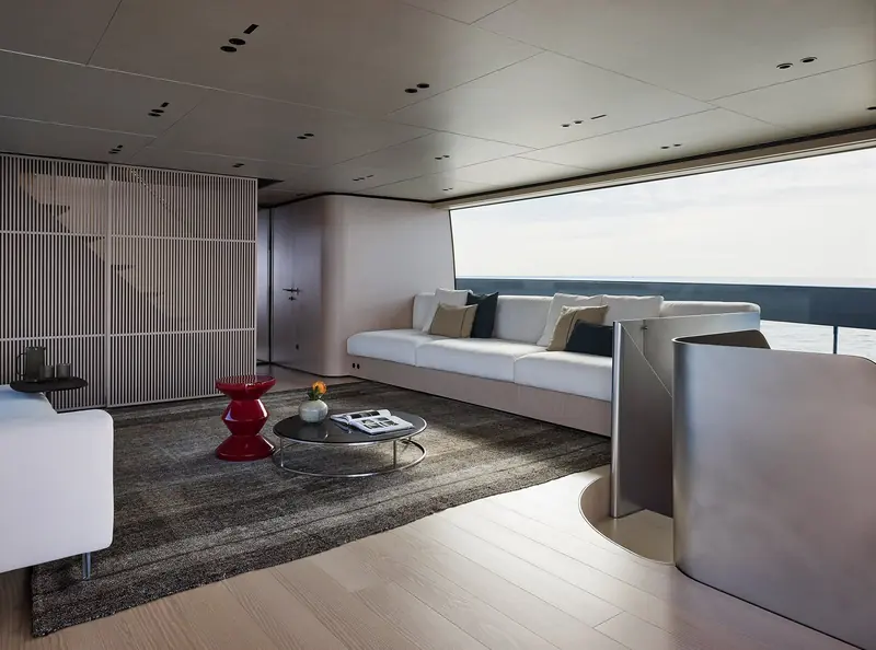 A secondary lounge area with a red accent stool against pale wood panelling.