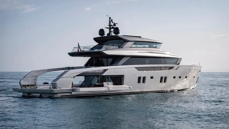 The first SX112, Almax, at anchor flying the Italian courtesy flag from her flybridge rail. The full-length starboard cutout that opens the hull side down to the water line, rather than a conventional flybridge overhang, is the SX line's signature and the reason the class is called a crossover rather than a motor yacht.