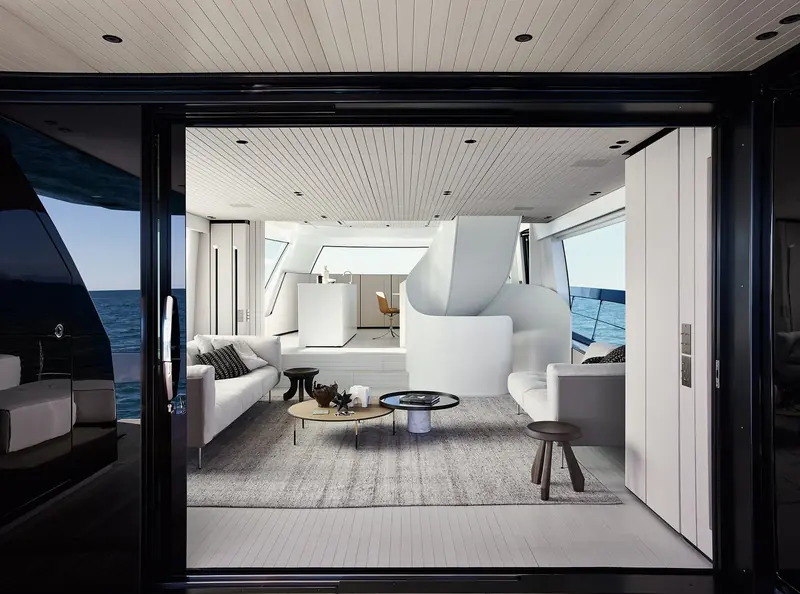 The main-deck saloon in white and grey, sliding glass doors open to the side deck.