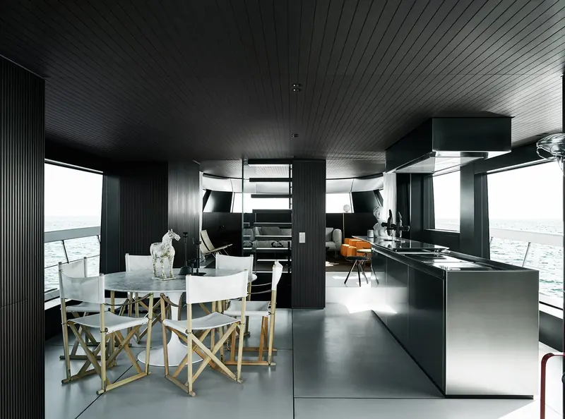 The galley and saloon in the SX88's dark palette, director's chairs around a marble-topped island.