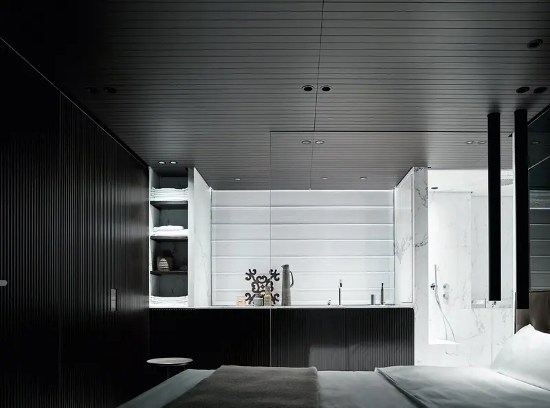 A cabin corridor in black wood leading to a marble-lined ensuite.