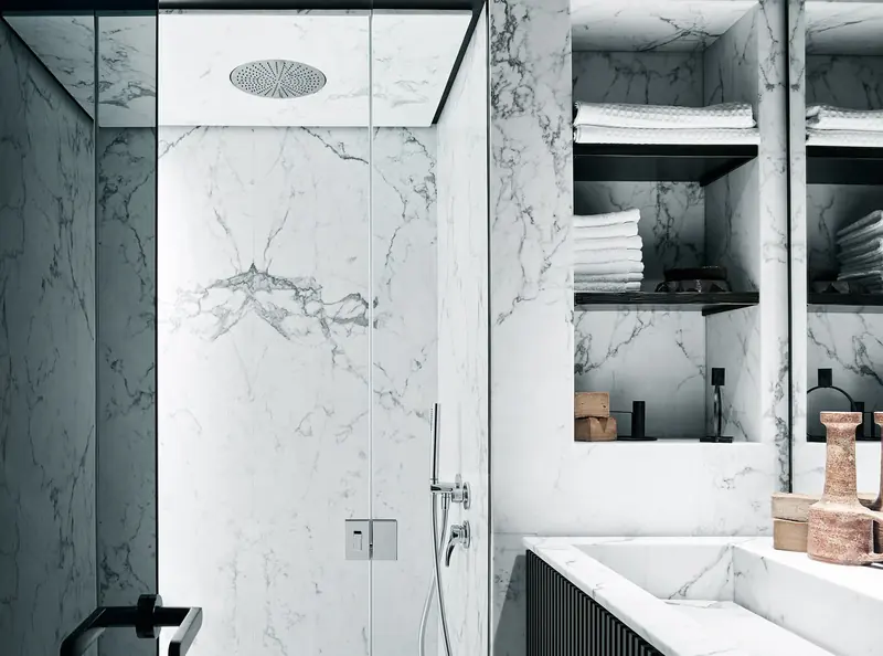 An ensuite shower finished floor to ceiling in book-matched white marble.