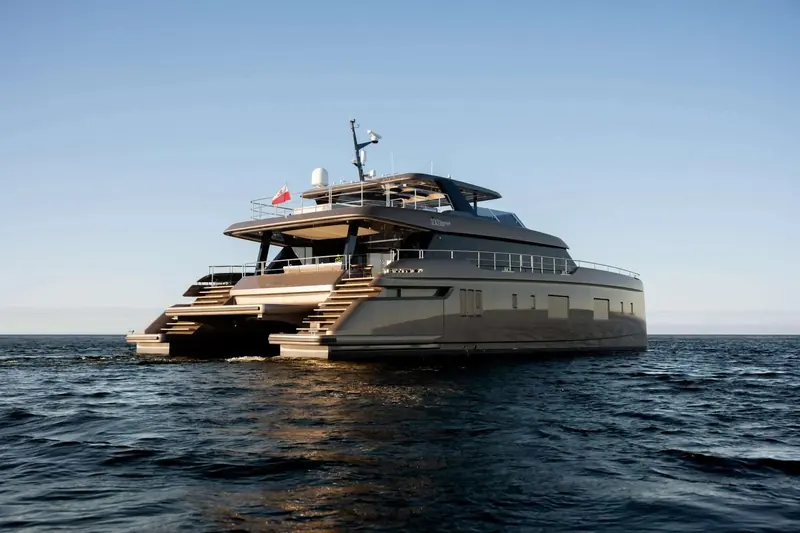 The 100 Sunreef Power Eco at rest, low evening light picking out the teak side decks and swim platforms.