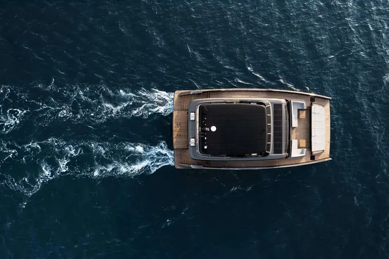Overhead view of the catamaran underway, twin hulls and full-beam flybridge clearly laid out.