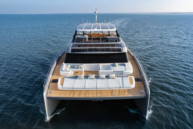 A stern-quarter view underway, showing the open aft deck and flybridge lounge above.