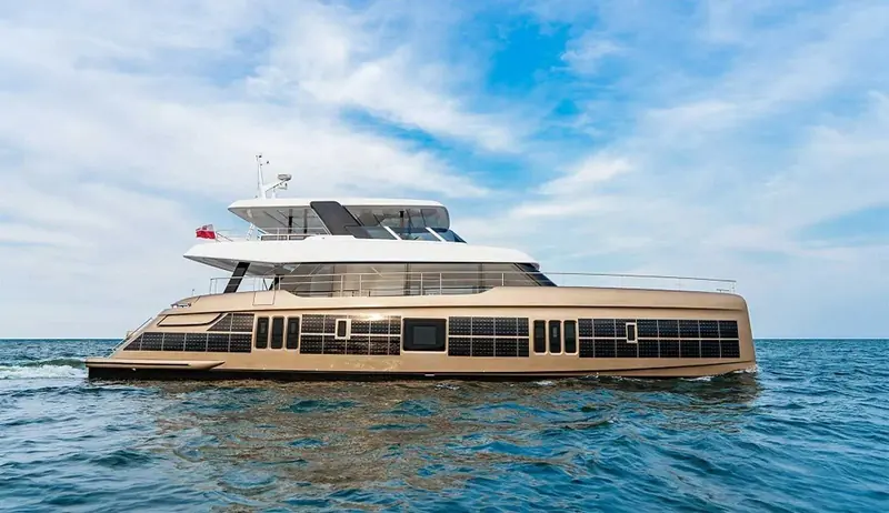 A broadside cruising shot in golden-hour light, full hull profile from bow to stern.