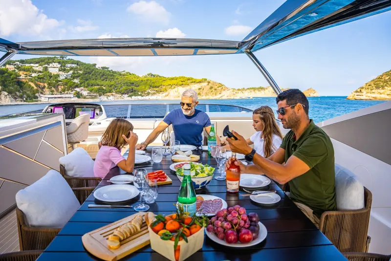 Lunch laid out on the flybridge table in a sheltered anchorage, showing the space used for dining rather than just sunbathing.
