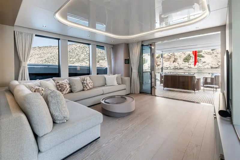 The saloon opens straight onto the covered aft deck through a full-height sliding door, so the two spaces read as one room at anchor.