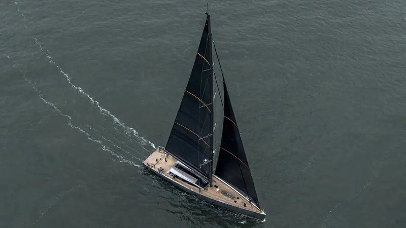 Magic under sail, seen from above, her dark hull and tan-coloured sails set.