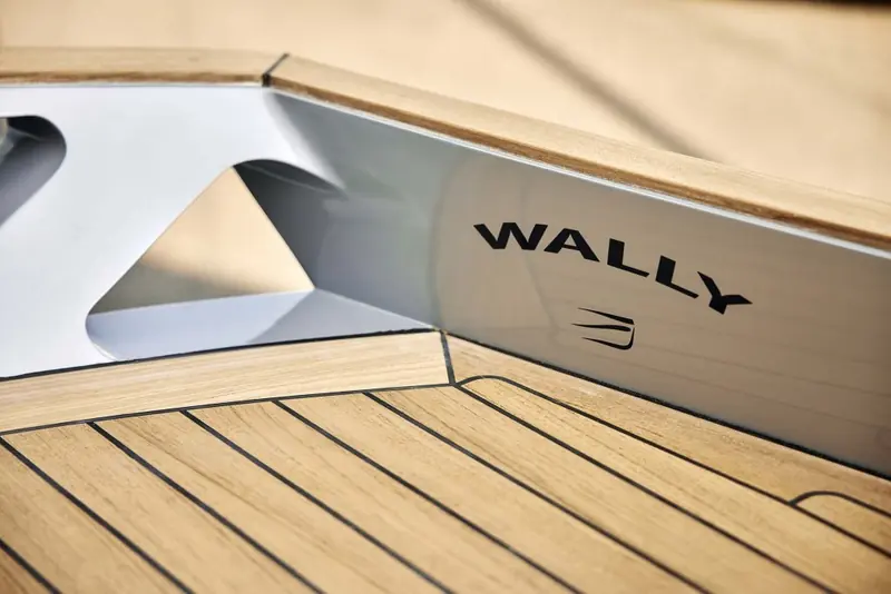 A detail of the stern quarter and Wally nameplate, showing the hand-finished teak deck and hard chine that mark the yard's build quality even on its smallest model.