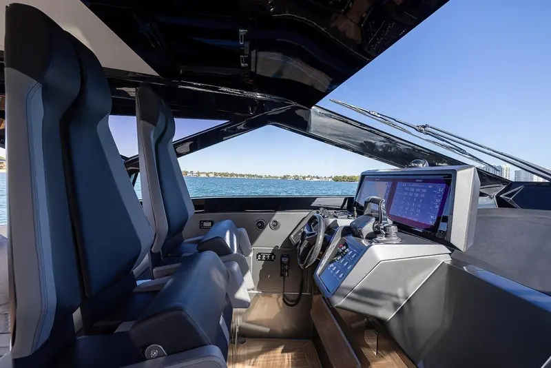 The helm station is stripped to a single central touchscreen and a pair of bolstered bucket seats, closer to a high-performance sportboat than a motor yacht bridge.