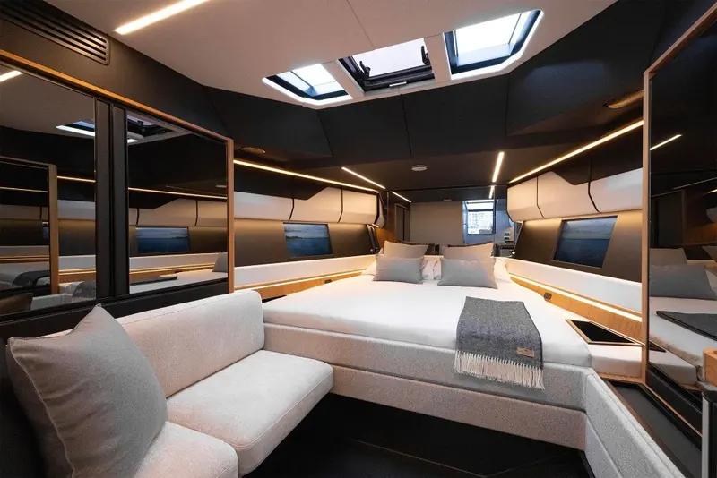 Below deck, a full-beam cabin with overhead skylights fits a proper berth and lounge into a boat whose exterior reads as a dayboat.